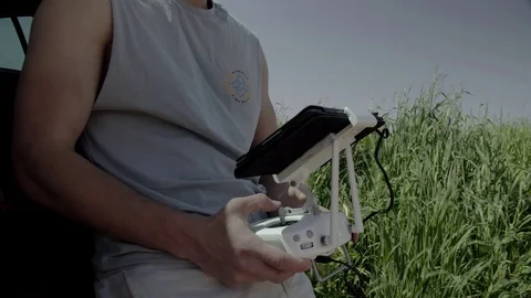 Young man controlling drone standing in the field with a remote his In hands. Stock Footage 116152869