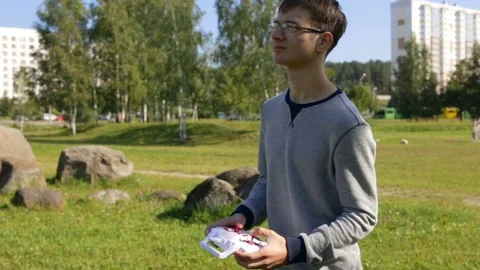 A young man, controls the quadcopter approaches the camera. Side view, camera mo Stock Footage 84913483