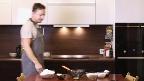 Young man cooking and making a cake in the kitchen at home, singing and dancing Stock Footage 93345981