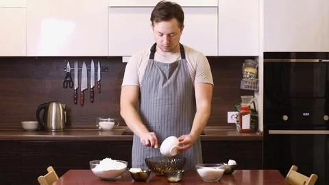 Young man cooking and making a cake in the kitchen at home, singing and dancing Stock Footage 93346307