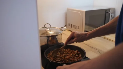 Young man cooking in the kitchen spaghetti bolognese fries mince with sauce in a Stock Footage 111399934