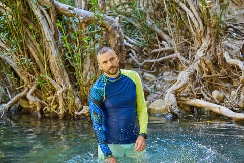 A young man cools off in the cold water of a mountain river on a hot summer d Stock Photos