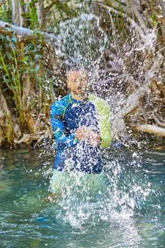 A young man cools off in the cold water of a mountain river on a hot summer d Stock Photos