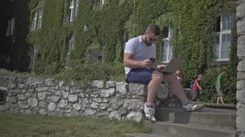 Young man is coping data from smartphone to laptop. Vídeo Stock 65524475