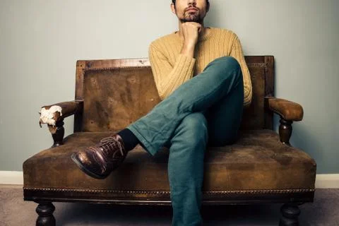 Young man on couch deep in thought Photos