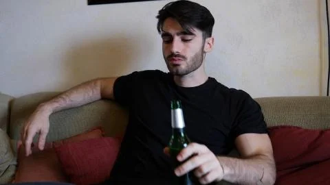 Young man on couch drinking beer Stock Photos