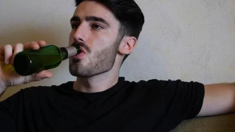 Young man on couch drinking beer Stock Photos