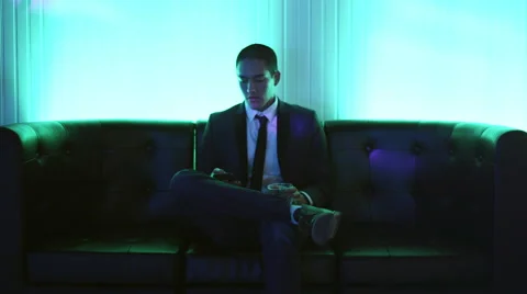 Young man on a couch in a nightclub taking a selfie with his phone Stock Footage