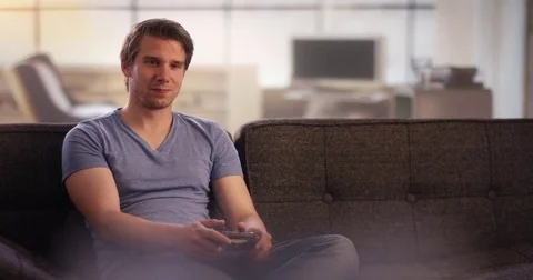 Young man on couch playing on a console Stock Footage 78626720