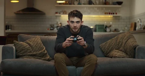 Young man on couch playing a video game with determination, skill and expertise. 스톡 동영상 87592678