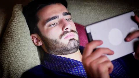 Young man on couch reading with tablet PC Stock Photos