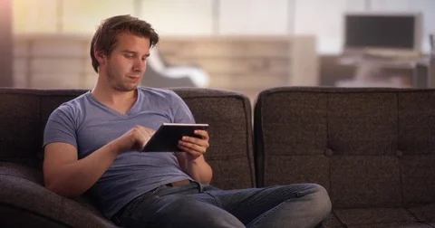 Young man on couch using his tablet Stock Footage 78627569