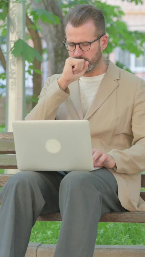 Young Man Coughing while Using Laptop Sitting Outdoor, Vertical Video Stock Footage 319019458
