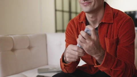 Young man counting cash while sitting on sofa, satisfied with startup profits Stock Footage 337908360