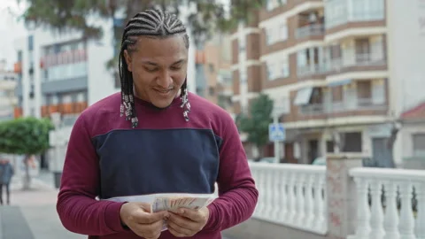 Young man counting pesos banknotes with both hands, smiling and looking dow.. Stock Footage 337361494