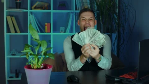 Young man counts money, sitting in armchair before computer in office Stock Footage 160446822