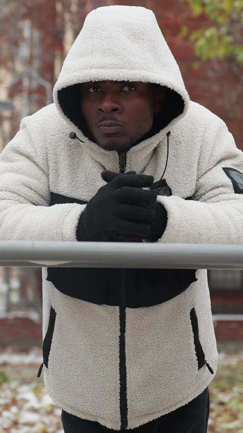 Young Man Cracks Knuckles Resting on Iron Bar in Cold Urban Environment Stock Footage 318582676