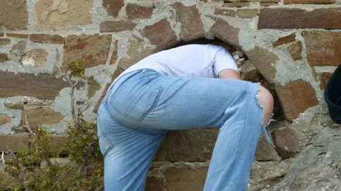 The young man crawls through the hole in the wall. Stock Footage 96861990