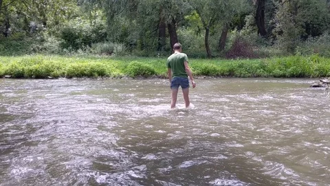 A young man crosses a river Stock Footage 112882871