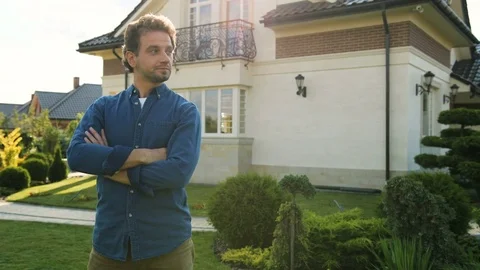 Young man with crossing hands smiling to the camera on the garden background. Stock Footage 78237864