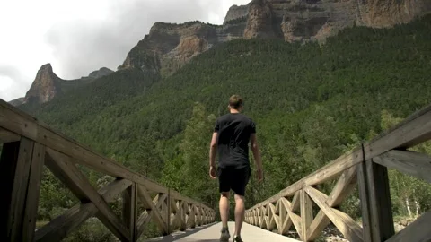 A young man crossing over a bridge while hiking in Ordesa y Monte Perdido Stock Footage 290262852