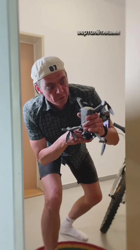 Young man crouched in doorway holding quadcopter drone with urgent expression Vidéo 344584352