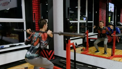 Young man crouches and rises with a bar in the gym 스톡 동영상 87828683