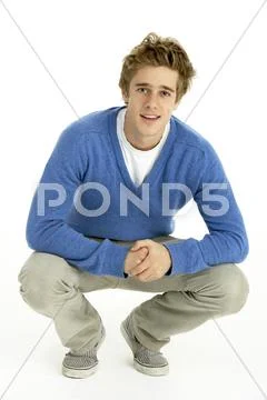 Young Man Crouching In Studio Stock Photos