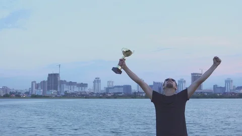 A young man with a cup in his hands at city evening. Concept as victory, success Видео 93820128