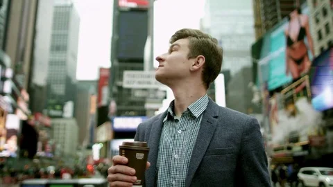 Young man with a cup of tea looking around on Times Square 動画素材 79593276