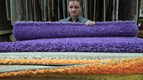 Young man customer selecting carpet covering for his house at shopping mall 4k Stock Footage 88116631