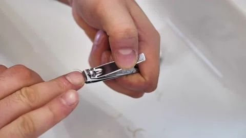 A young man cuts his nails over the sink by Clippers. Close-up hands Stock Footage 148988308