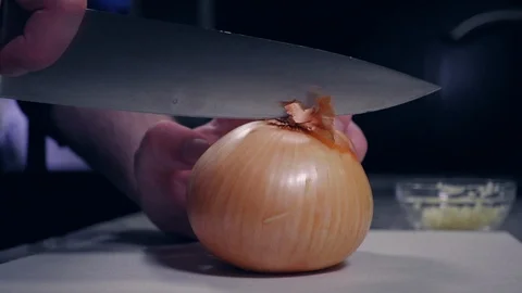 Young man cuts onion in half with chef knife. Stock-Footage 118330847