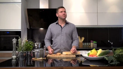 Young man cuts, smells and tastes baguette. Slider shot. Video stock 70592180