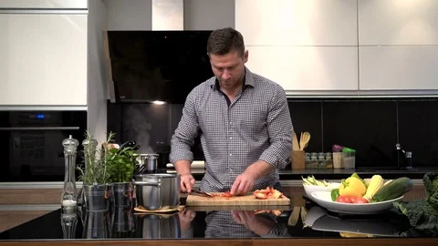 Young man cutting pepper, smiles to camera. Slider shot. Vídeo Stock 70590108