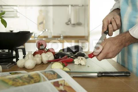 Young man cutting vegetables in kitchen, close-up Stock Photos