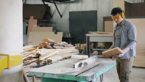 Young man cutting wooden plank with electric circular saw in workroom Stock Footage