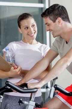 Young man on cycle machine with trainer Stock Photos