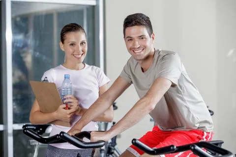 Young man on cycle machine with trainer Stock Photos
