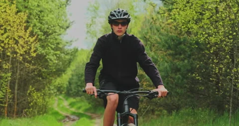 Young  man cyclist rides on a forest road. Teenager on a mountain bike rides Stock Footage 135915899