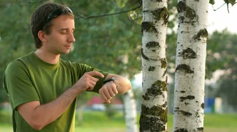 A young man cyclist touch smart watch near the birch . Against the background of Stock Footage 66454532