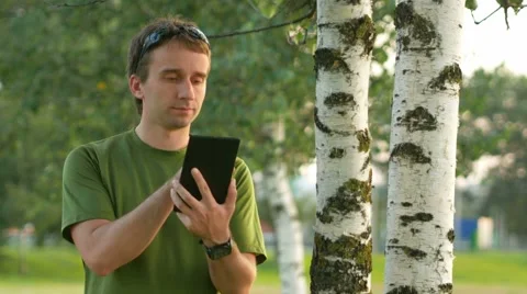 A young man cyclist touch tablet near the birch . Against the background of Stock Footage 66453878