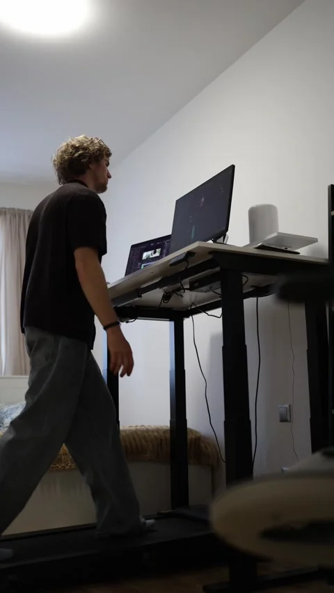 Young man dances while editing video at computer enjoying creative work and movi Stock Footage 346880513