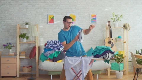 Young man dancing and Ironing clothes slow mo Stock Footage 106810631