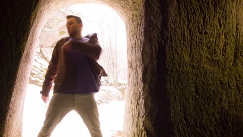 Young man dancing in the cave doorway Stock Footage 82424128