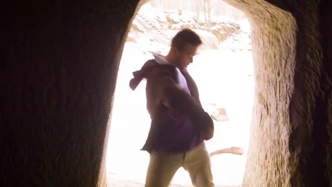 Young man dancing in the cave doorway 스톡 동영상 82452906