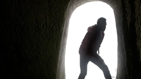 Young man dancing in the cave doorway 動画素材 82588446