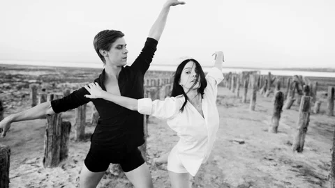 Young man dancing classical ballet with beautiful woman outdoors on sandy coast Stock Footage 118210653