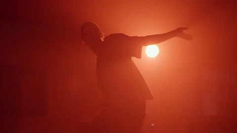 Young man dancing contemporary hip hop on red neon background in studio wearing Stock Footage 253576880