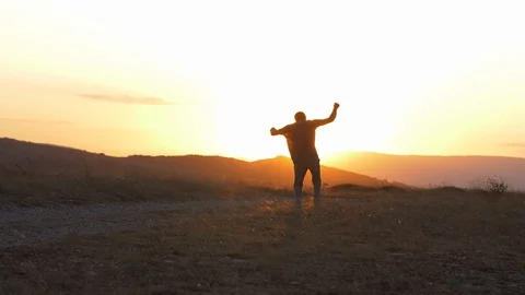 Young man dancing on a dusty road in the mountains in the sunset light Stock Footage 117608057